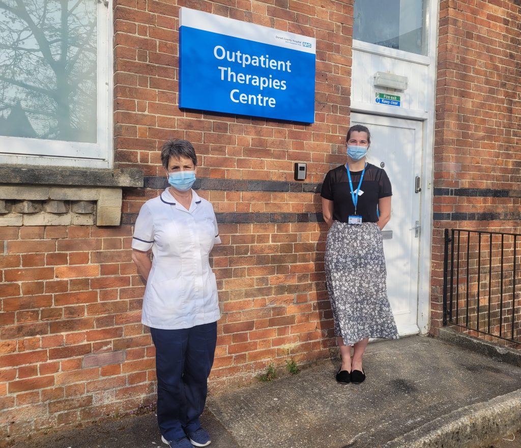 taff outside the Outpatient herapies Centre. Red brick, white door and blue sign