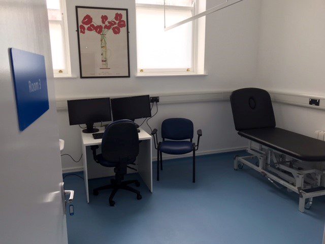 Clinic room. With bed, desk, chair and big windows