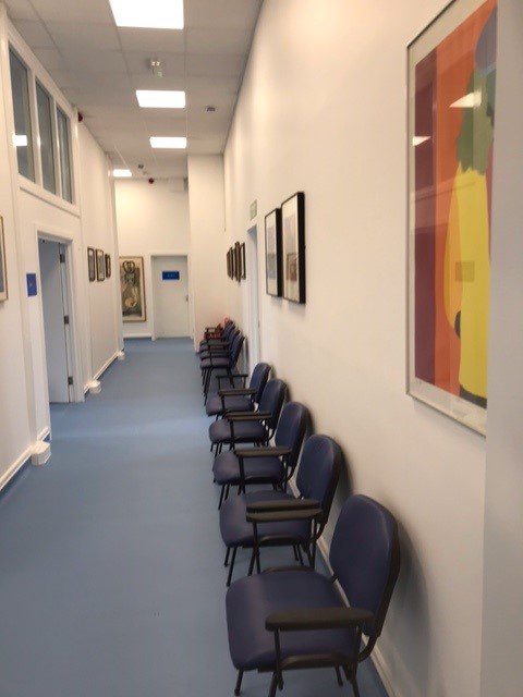 Waiting area with seats in a long corridor and art on the walls
