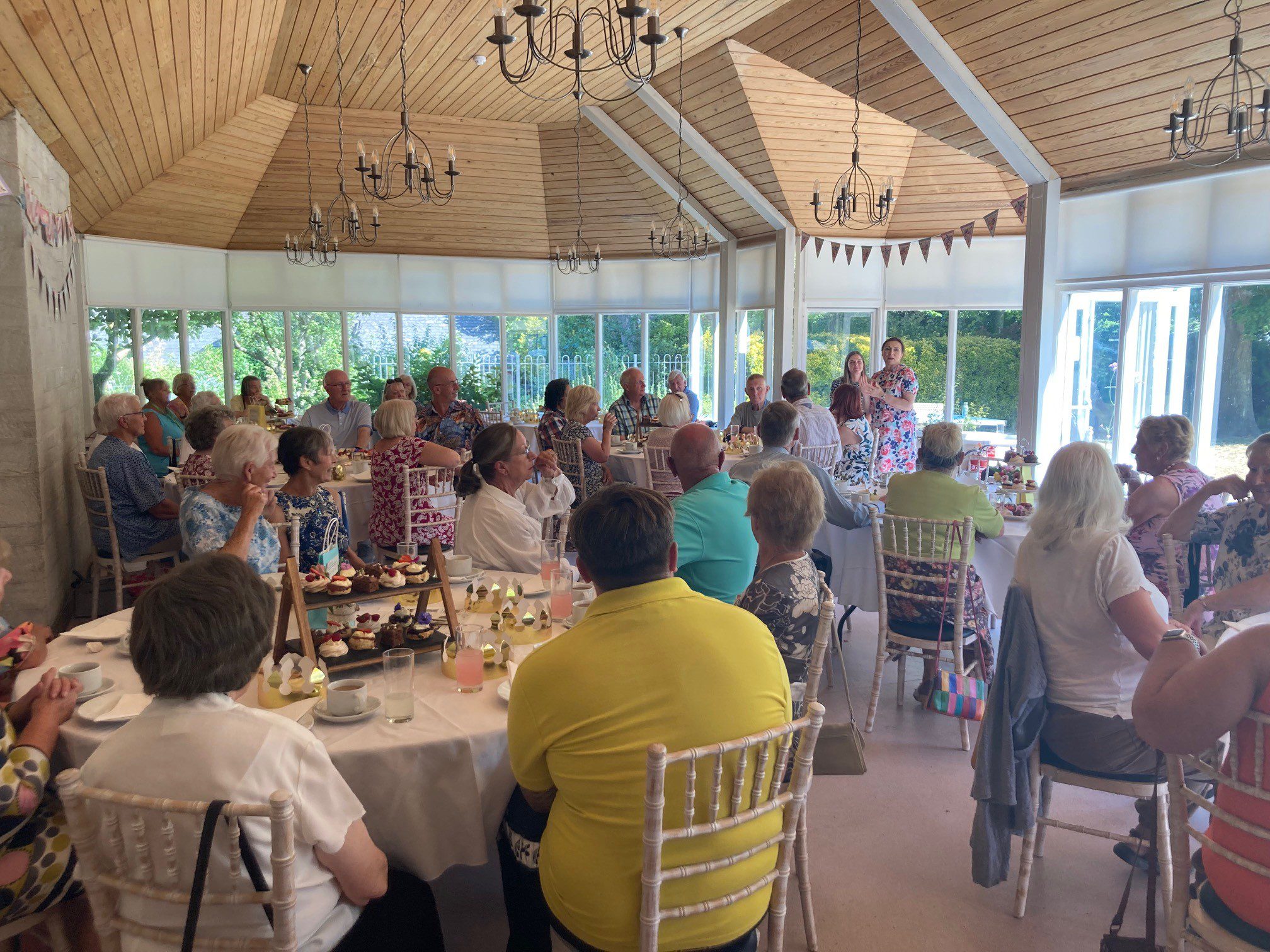 Guests sat at tables with tea and cake at our party for volunteers