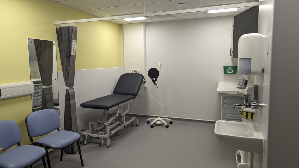 Clinic room with bed and chairs. Yellow walls