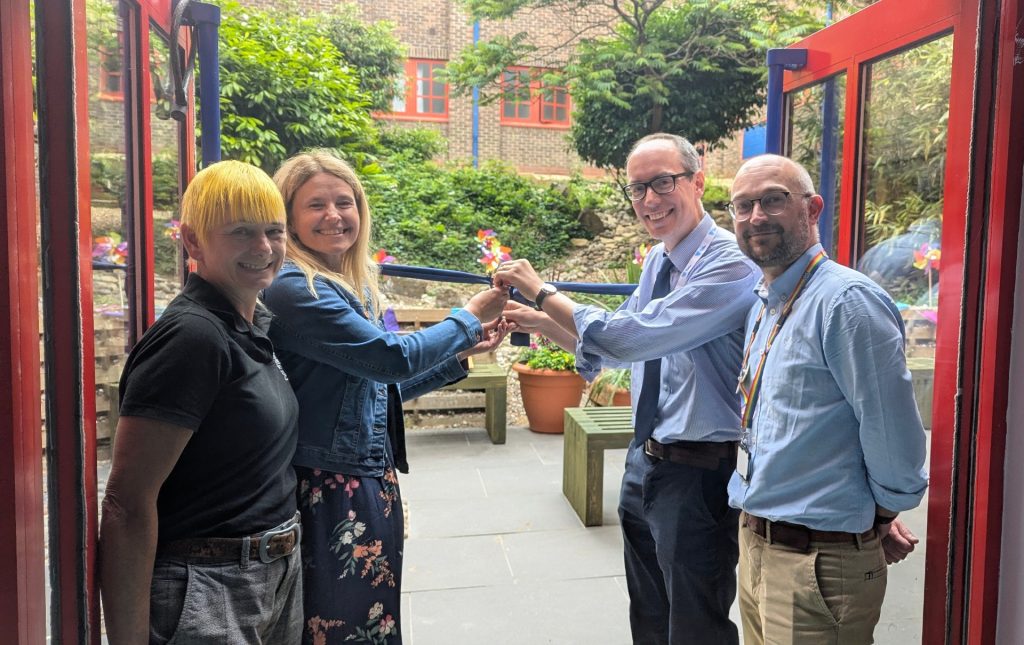 Opening pic People stood with ribbon and scissors in doorway to the sensory garden